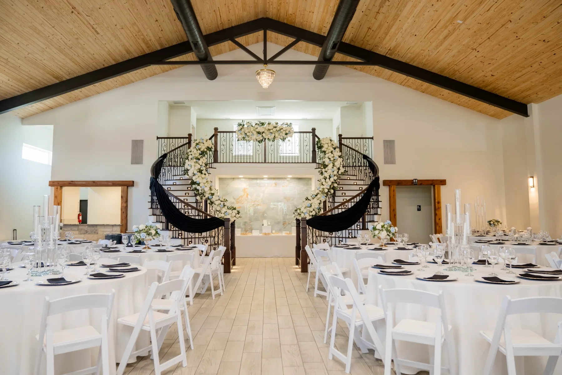 Wedding reception hall with grand staircase and white floral arch