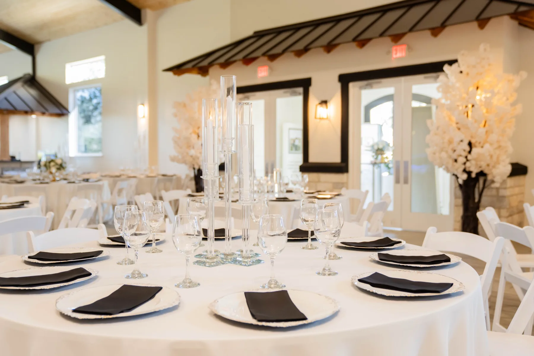 Elegant white tablescape with glass candle holders and black napkins