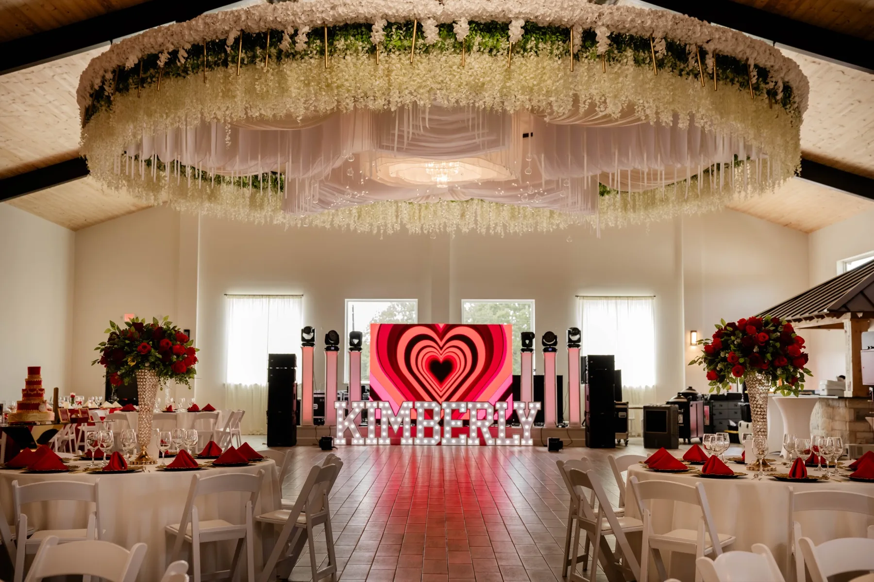 Quinceanera reception dance floor with red decor and floral ceiling installation